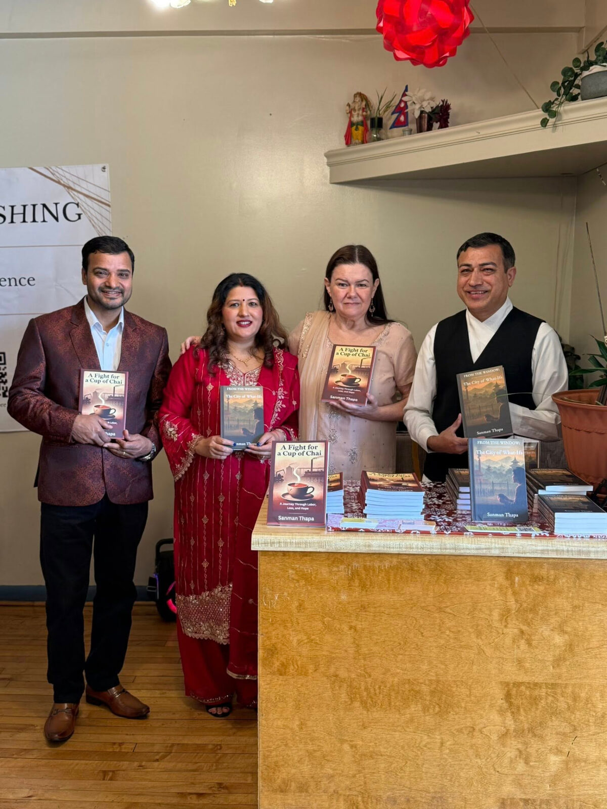 Four guests holding the books beside the display table