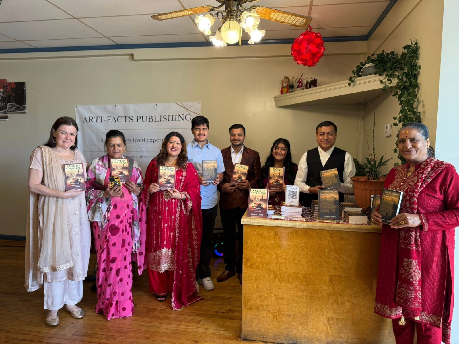 The full group with books in front of the Arti Facts Publishing banner