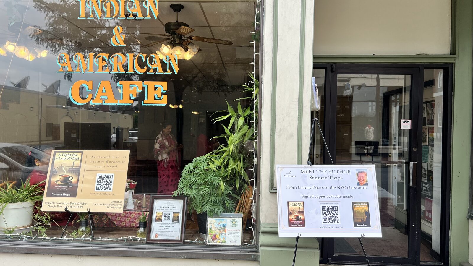 Cafe window display with book posters and the meet the author board