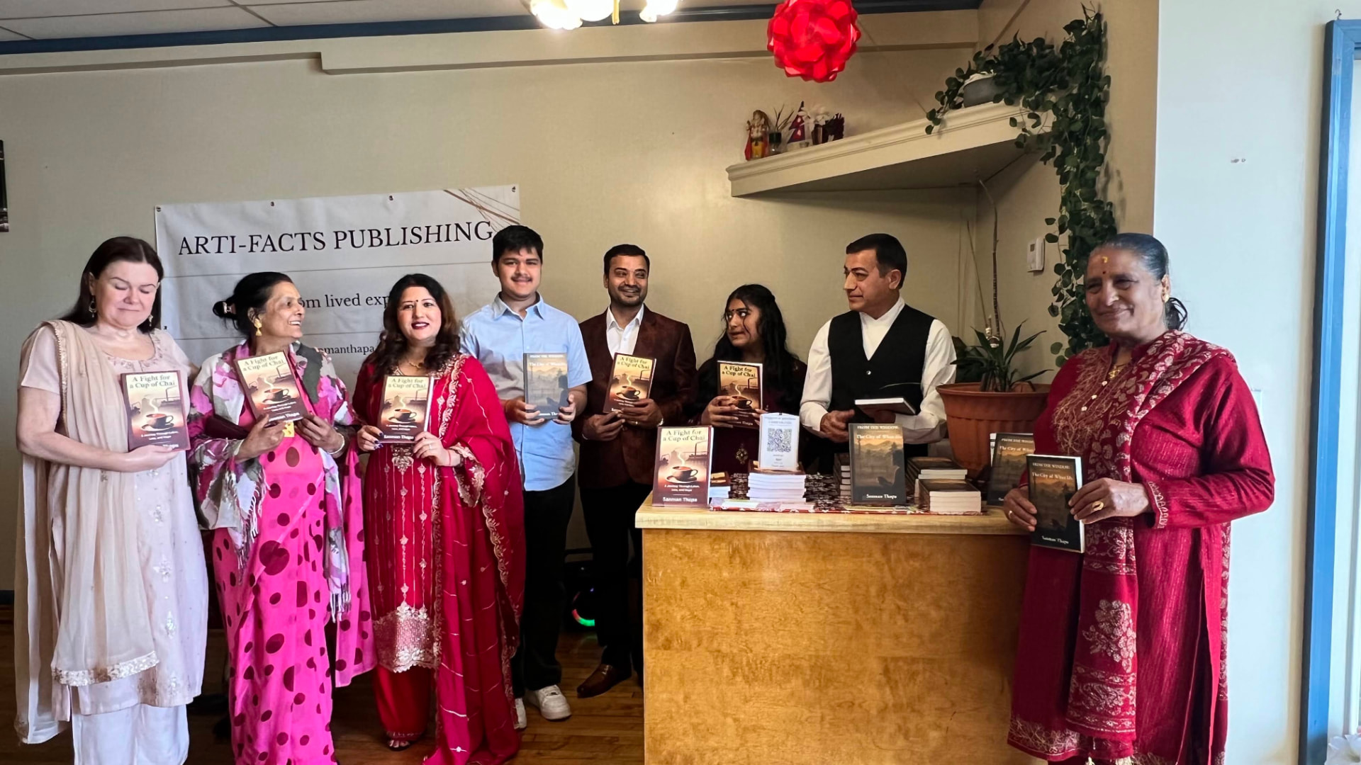 Guests holding copies of the books beside the Arti Facts Publishing banner