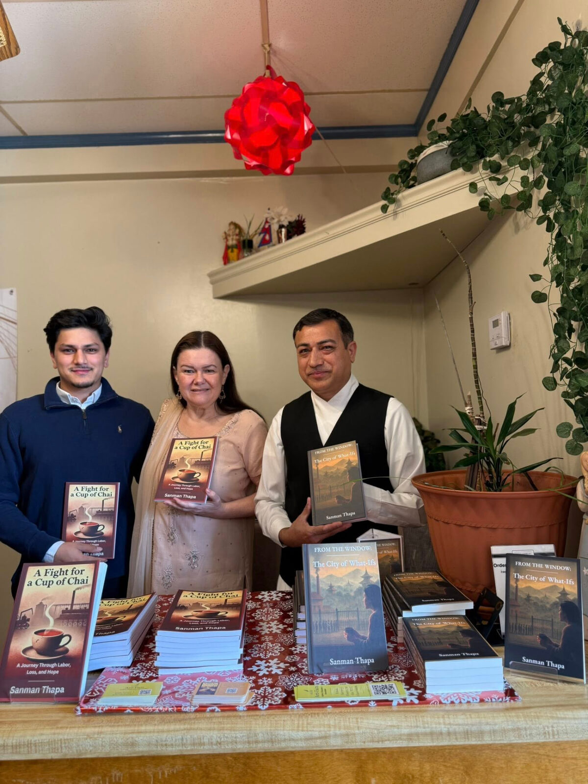 Three guests holding copies of both titles behind the launch table